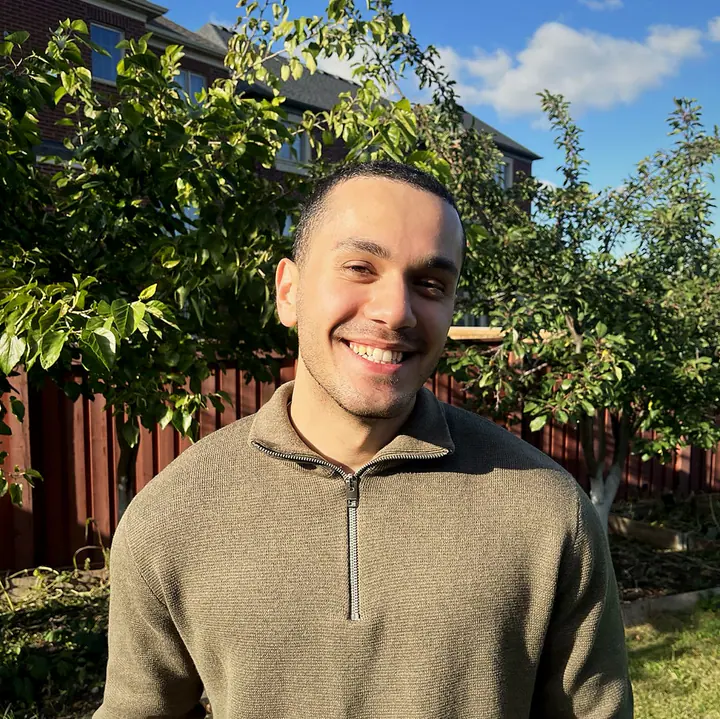 Ajmal Roshan smiling outdoors in a garden.